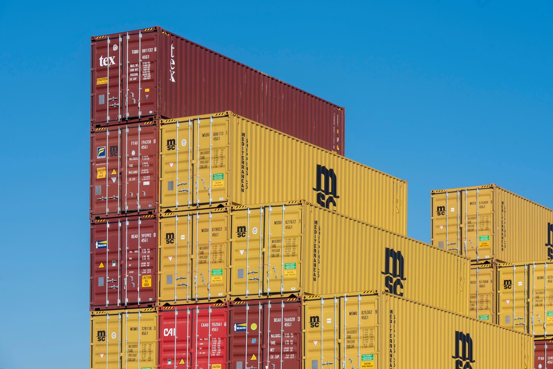 Stacks of shipping containers against a clear blue sky